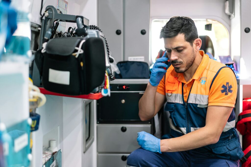 handsome paramedic talking on the phone inside an ambulance ready to attend to an emergency