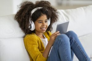 Closeup of adorable black girl using digital pad and headset